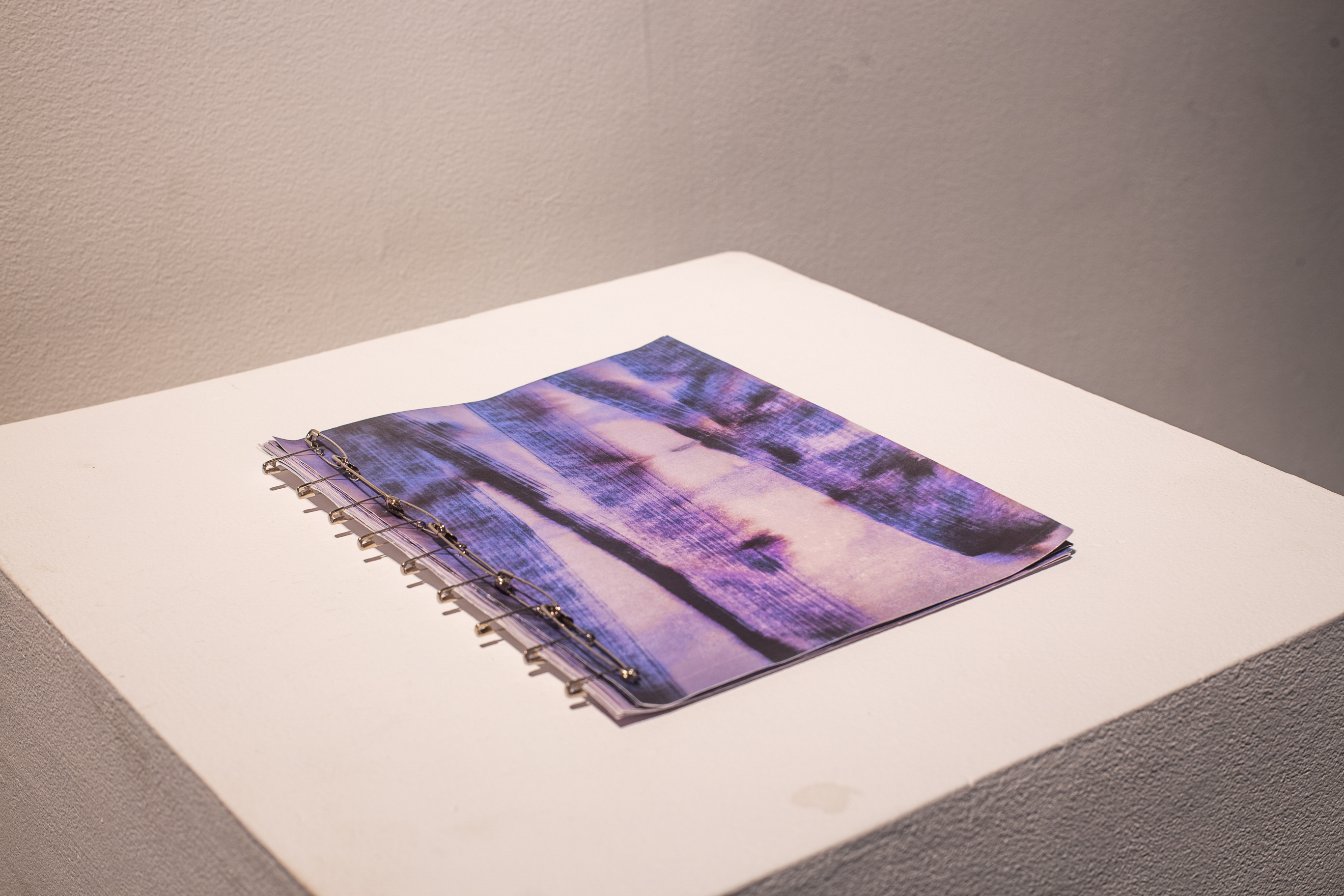 The purple cover of a book as it lays on a white podium.